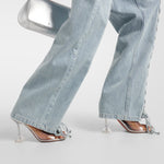 Light blue straight-leg jeans with lace-up side details and ankle ties, styled with clear heels and silver bag — Rotate | Endless UAE
