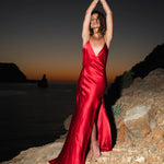 Woman in red silk backless maxi dress with high slit at sunset by the ocean — By Keara | Endless UAE