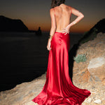 Elegant red satin backless evening gown with flowing train at sunset beach — By Keara | Endless UAE