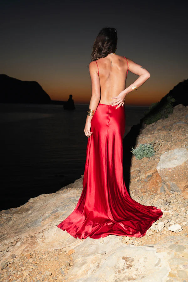 Elegant red satin backless evening gown with flowing train at sunset beach — By Keara | Endless UAE