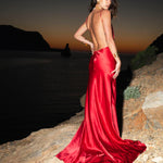 Elegant red satin backless maxi dress with flowing train, worn at sunset by the ocean — By Keara | Endless UAE