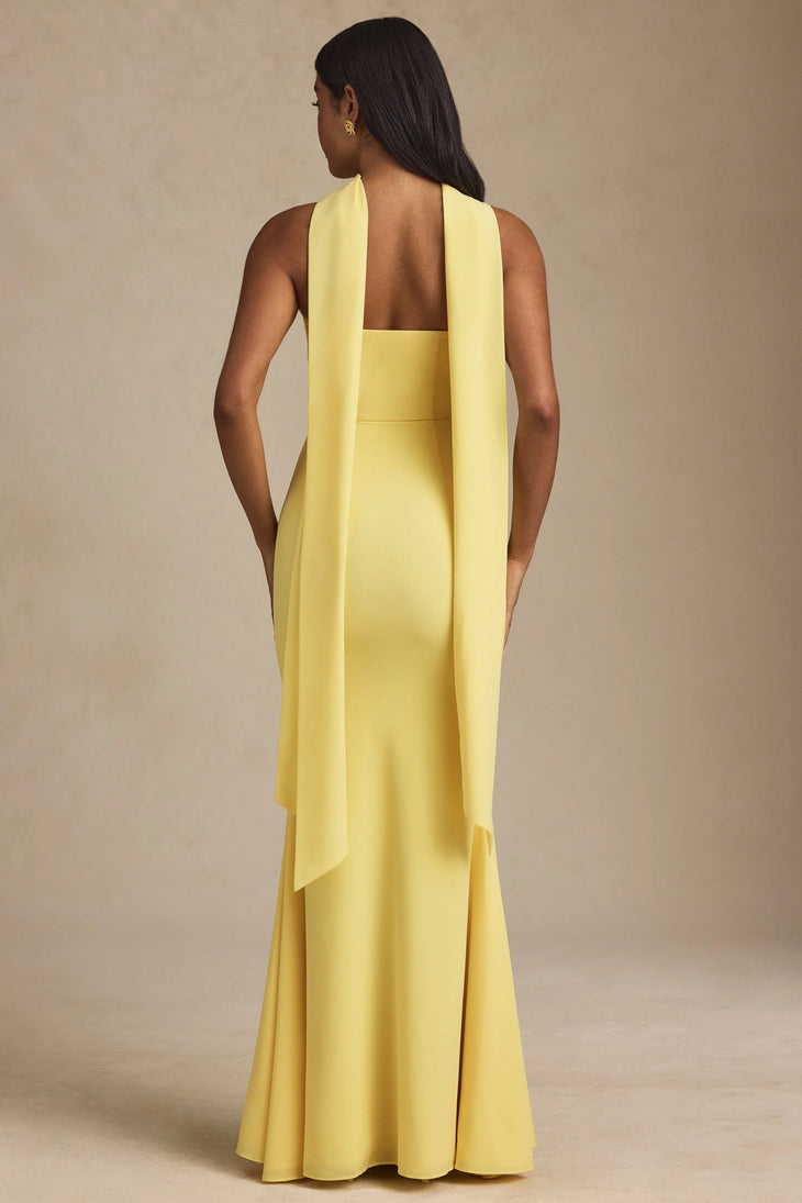 Woman wearing yellow strapless gown with draped scarf detail standing at entrance — Oh Polly | Endless UAE