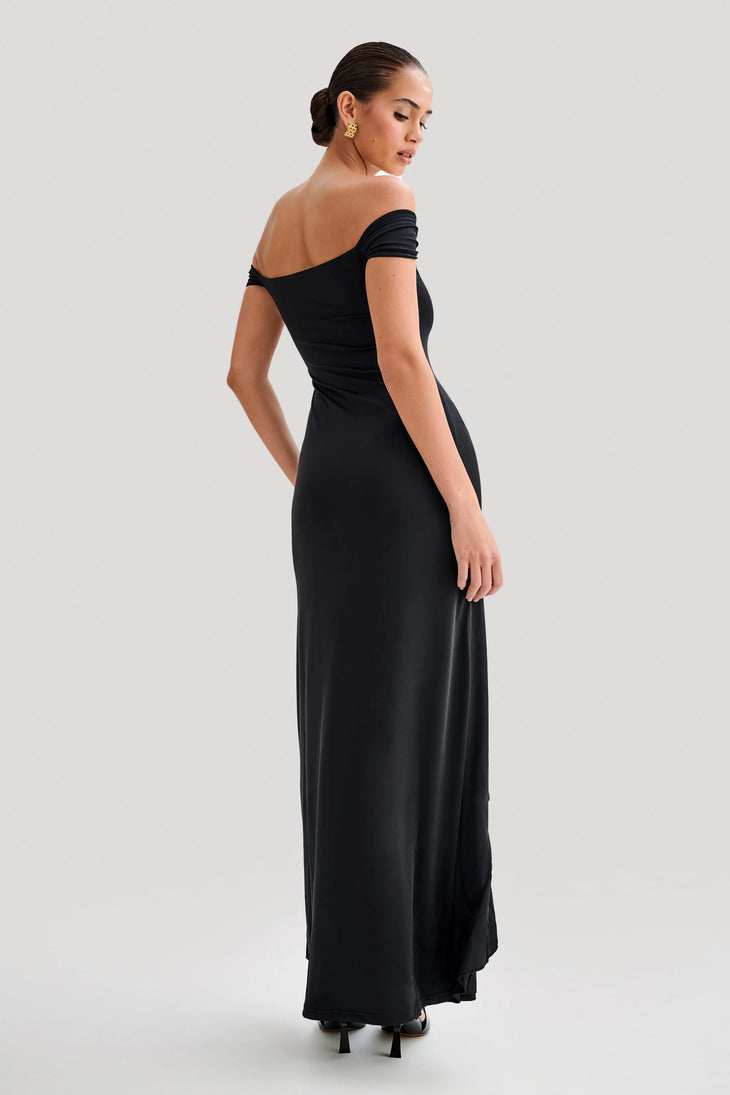 Woman wearing black off-shoulder slinky maxi dress with high-low hemline and gold hoop earrings — Meshki | Endless UAE