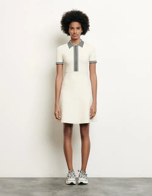 Woman wearing cream polo-style knitted dress with striped trim, sitting on chair — Sandro | Endless UAE