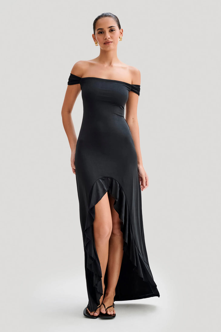Woman wearing black off-shoulder slinky maxi dress with high-low hemline and gold hoop earrings — Meshki | Endless UAE
