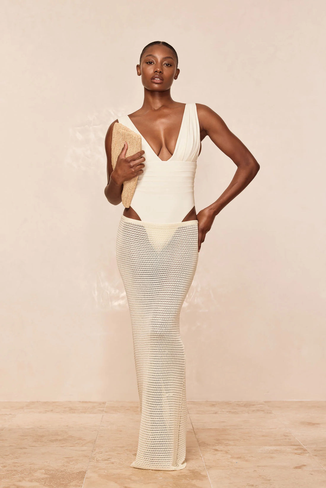 Woman wearing cream fitted midi skirt with matching bikini top and sheer shirt by the ocean — Monday Swimwear | Endless UAE