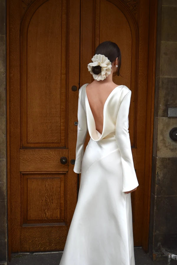 Bride in white satin Eden Dress holding white flowers — One Addington | Endless UAE