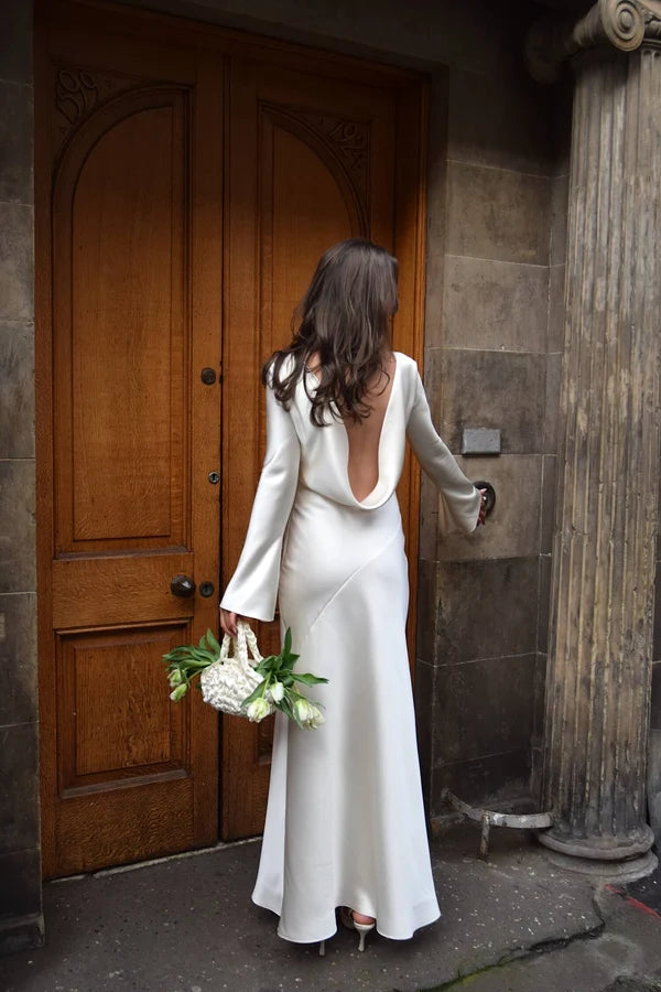 Bride in white satin Eden Dress holding white flowers — One Addington | Endless UAE