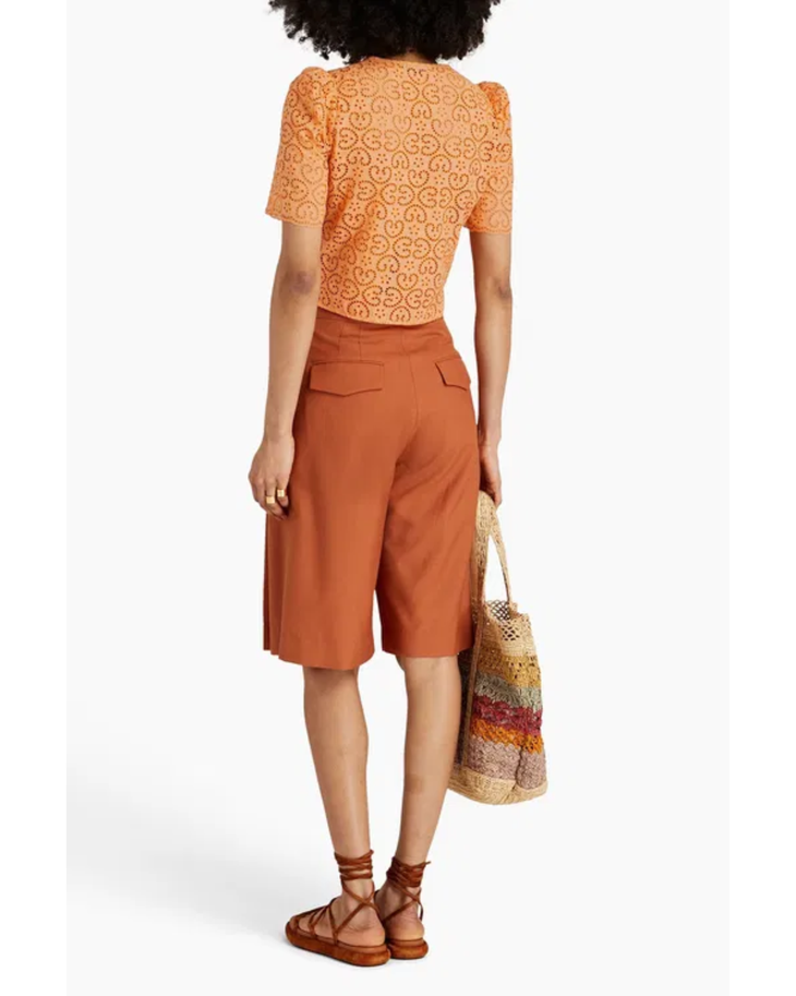 Woman wearing orange broderie anglaise top with matching culottes and woven bag — Sandro | Endless UAE