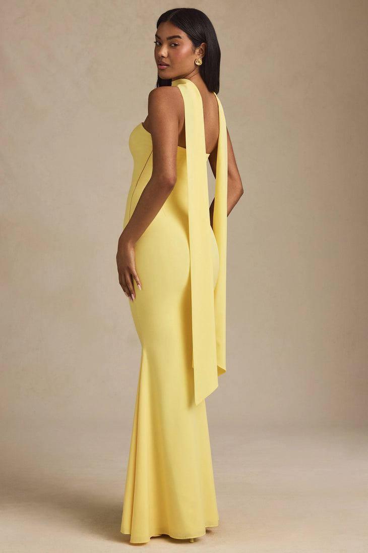 Woman wearing yellow strapless gown with draped scarf detail standing at entrance — Oh Polly | Endless UAE