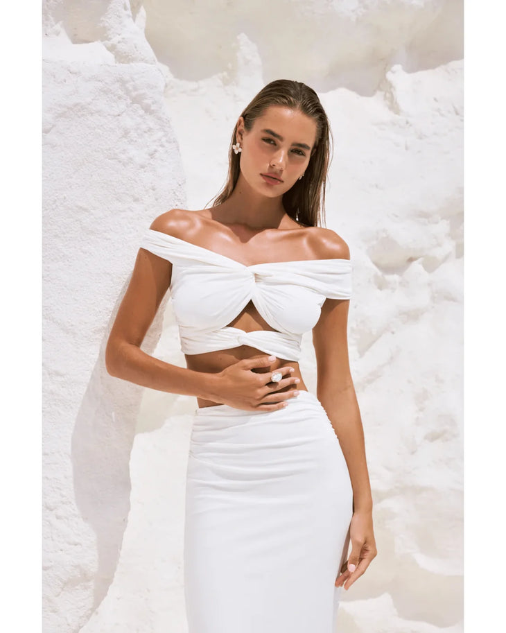 Woman wearing white off-shoulder crop top and maxi skirt in modern architectural setting — By Alle | Endless UAE