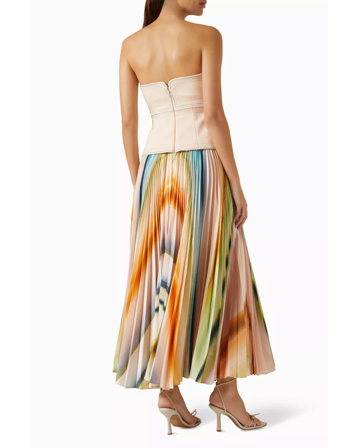 Woman wearing cream strapless top with colorful pleated midi skirt and neutral sandals — Acler | Endless UAE