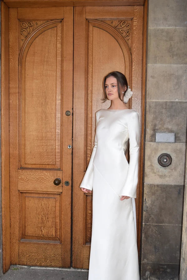Bride in white satin Eden Dress holding white flowers — One Addington | Endless UAE