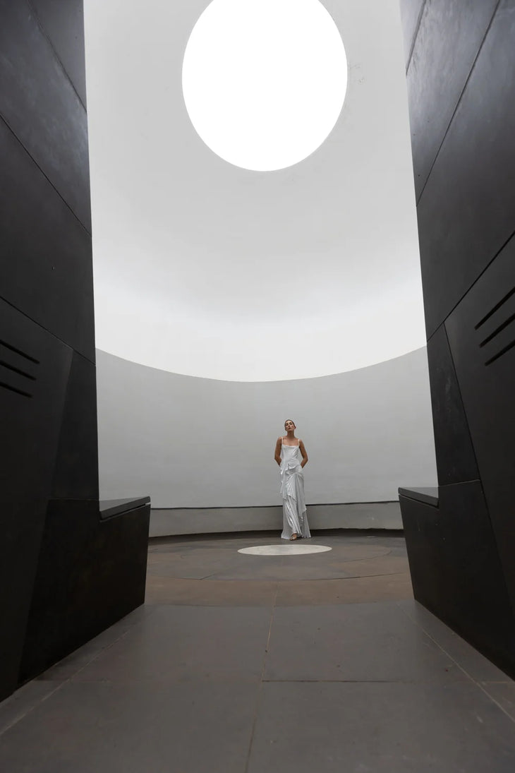 Woman wearing white draped Torrent Dress in modern architectural setting — Georgia Hardinge | Endless UAE
