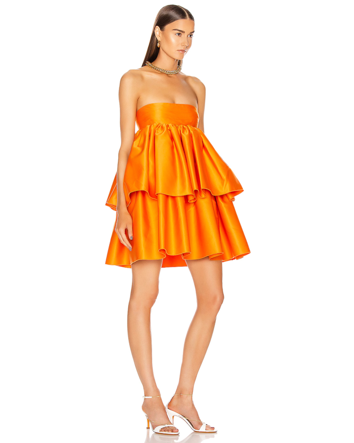 Woman wearing a strapless orange satin dress with tiered ruffled skirt and white sandals — Rotate | Endless UAE