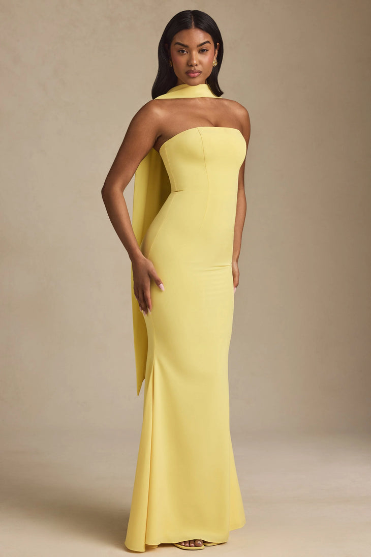 Woman wearing yellow strapless gown with draped scarf detail standing at entrance — Oh Polly | Endless UAE