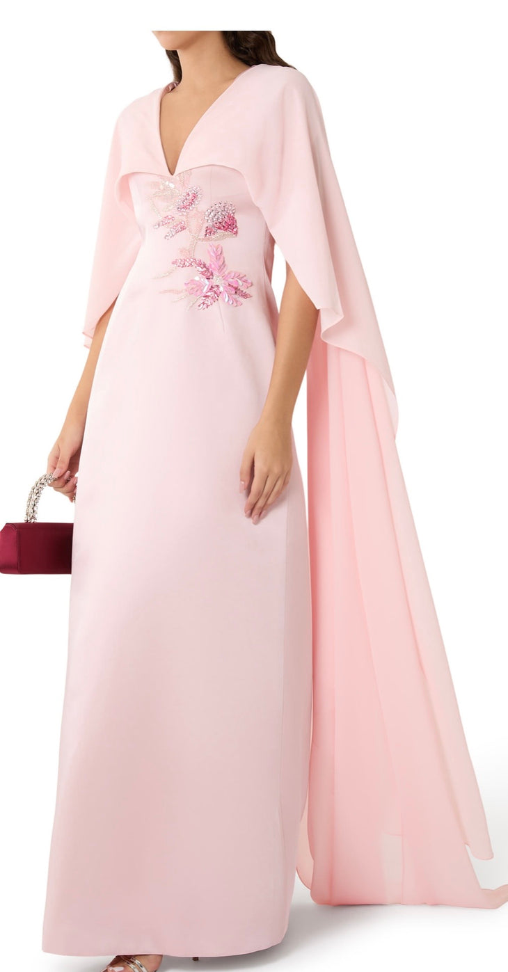 Woman wearing blush pink flowing gown with floral embellishment and draped cape at lakeside sunset — Tracy Studio | Endless UAE