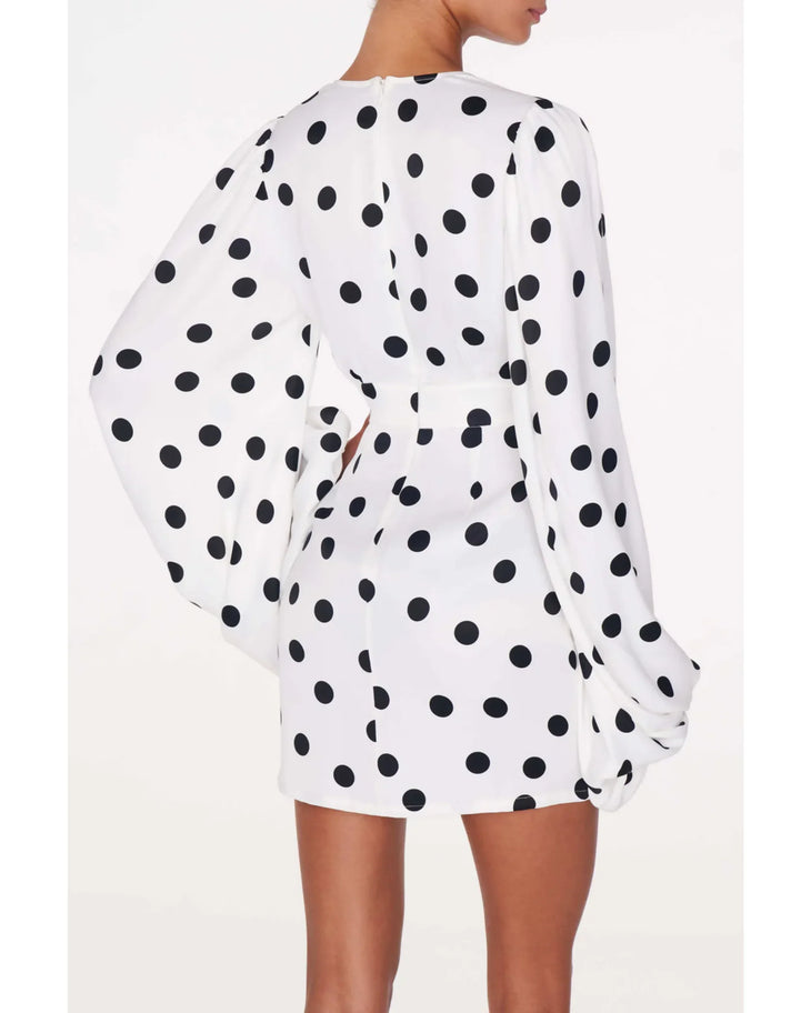 Perla Dress in white with black polka dots worn by a woman against a weathered brick wall — Rat & Boa | Endless UAE