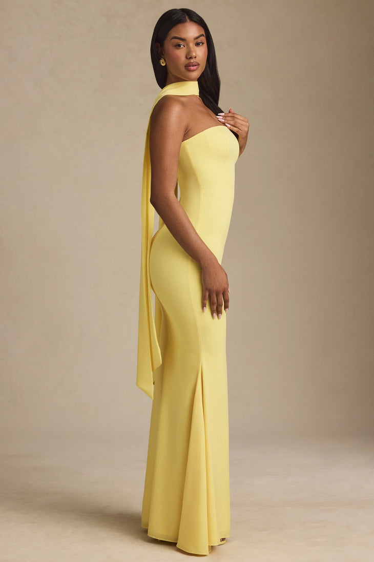 Woman wearing yellow strapless gown with draped scarf detail standing at entrance — Oh Polly | Endless UAE