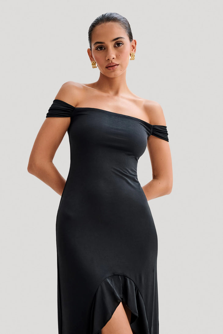 Woman wearing black off-shoulder slinky maxi dress with high-low hemline and gold hoop earrings — Meshki | Endless UAE