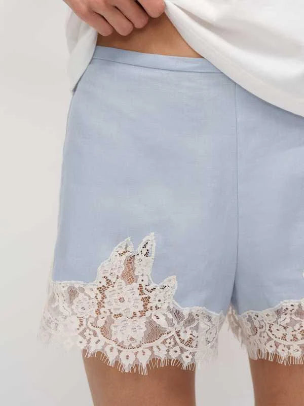 Woman wearing white t-shirt and light blue linen shorts with lace trim — Reformation | Endless UAE