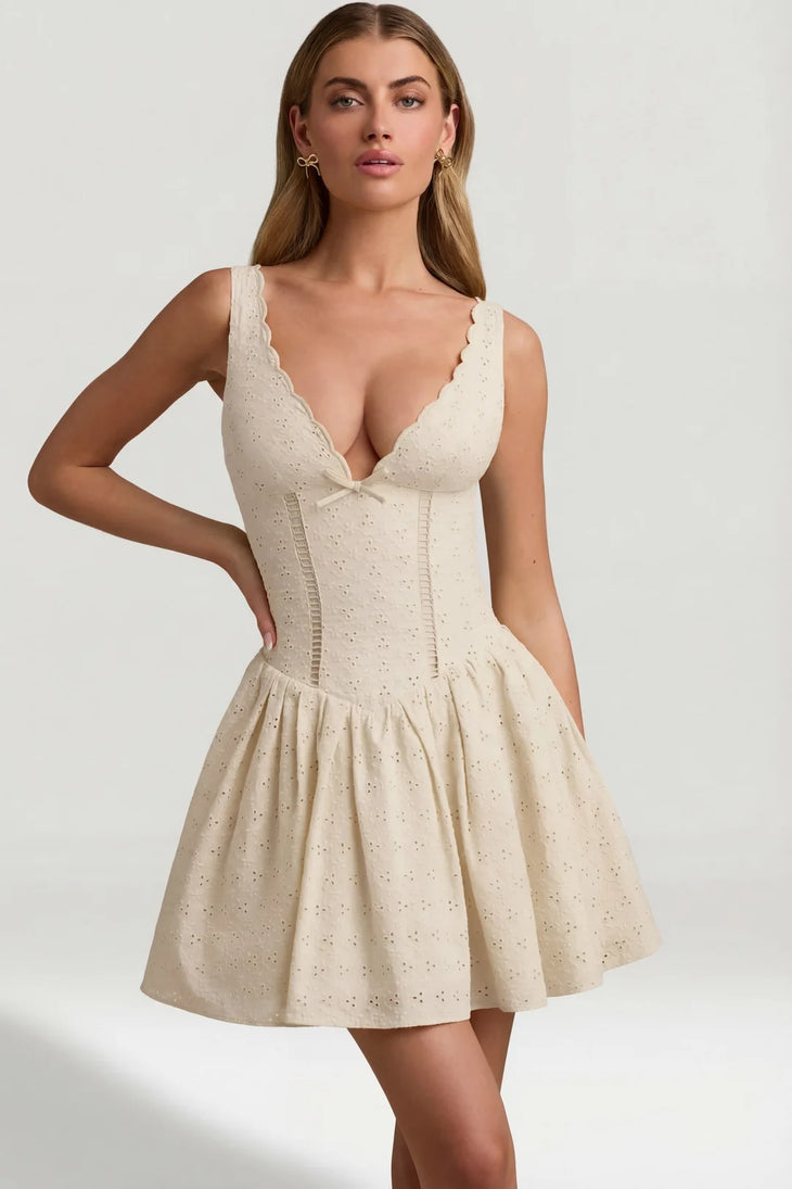Woman wearing cream broderie anglaise A-line mini dress with bow detail and strappy sandals — Oh Polly | Endless UAE