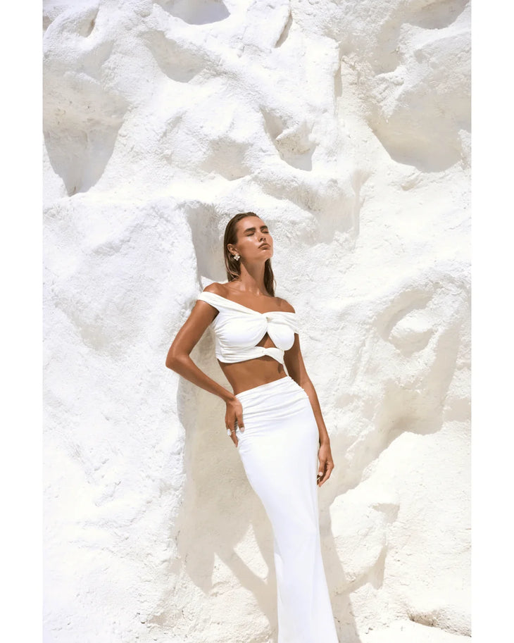Woman wearing white off-shoulder crop top and maxi skirt in modern architectural setting — By Alle | Endless UAE