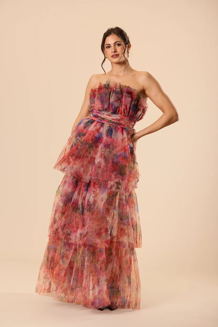 Woman wearing a strapless floral tulle maxi dress with tiered ruffle layers in red and pink tones — Lace & Beads | Endless UAE