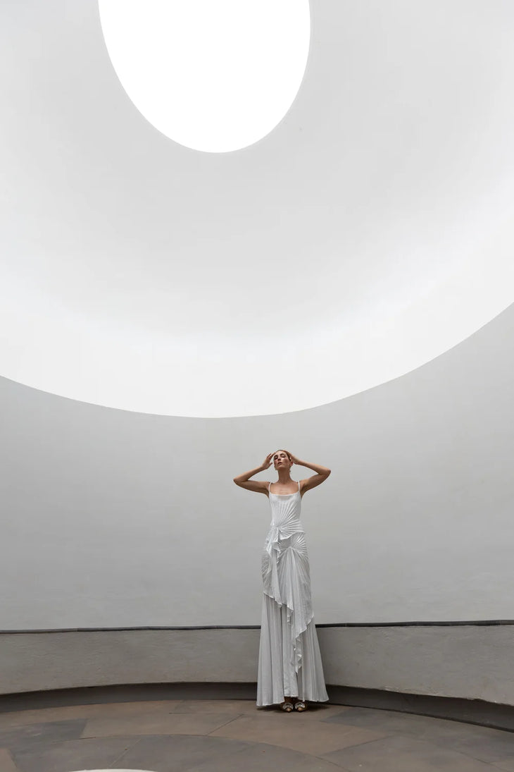 Woman wearing white draped Torrent Dress in modern architectural setting — Georgia Hardinge | Endless UAE