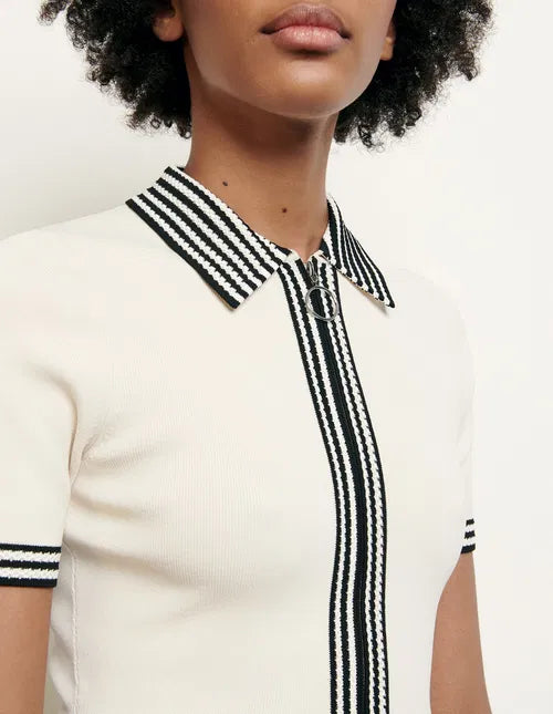 Woman wearing cream polo-style knitted dress with striped trim, sitting on chair — Sandro | Endless UAE