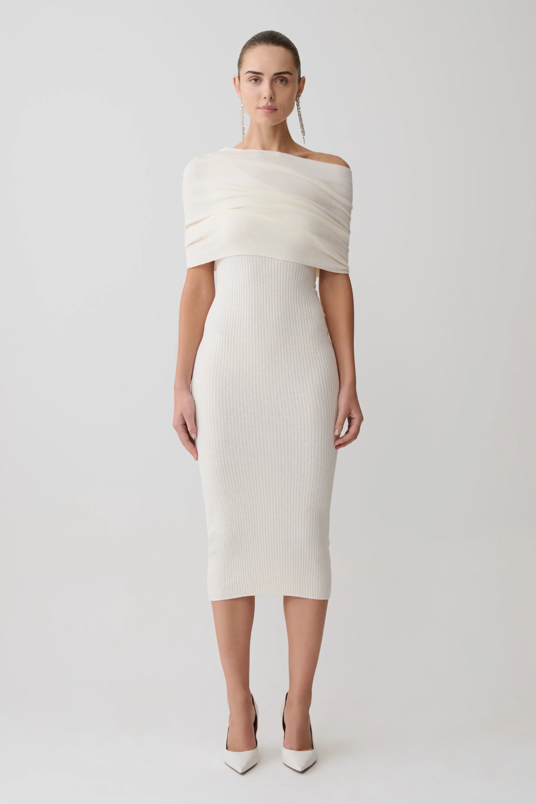 Woman wearing cream cashmere blend knit midi dress with draped off-shoulder overlay and white pointed heels — Meshki | Endless UAE