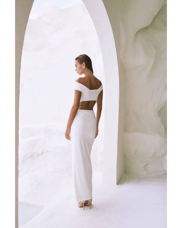 Woman wearing white off-shoulder crop top and maxi skirt in modern architectural setting — By Alle | Endless UAE