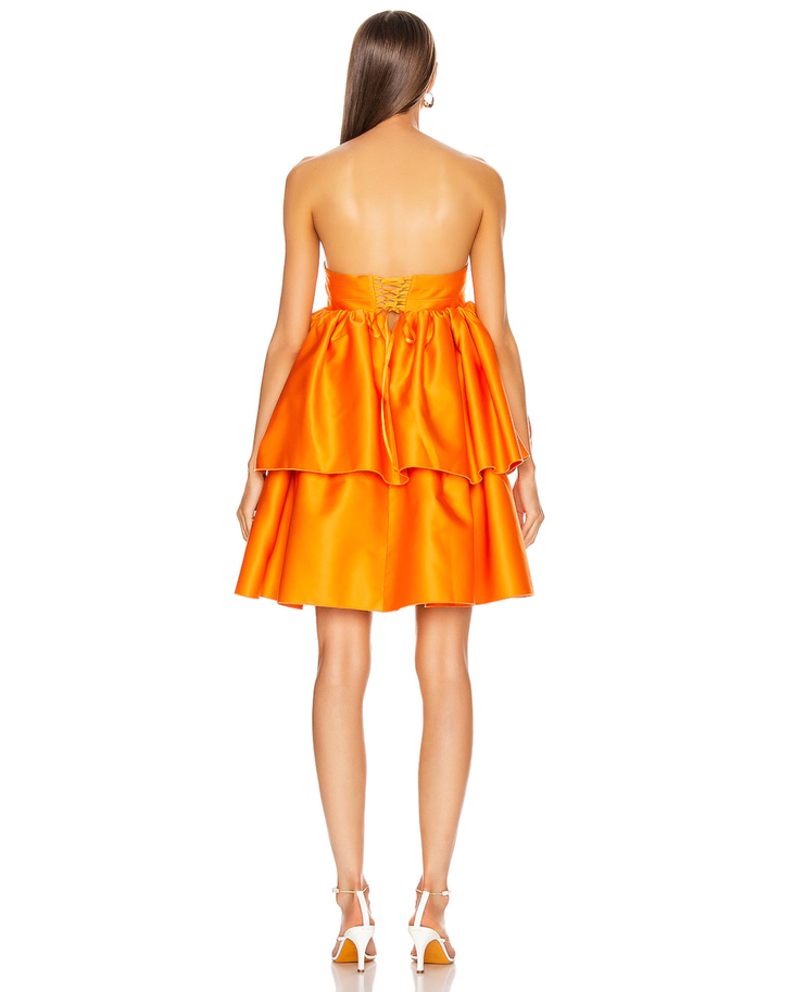 Woman wearing a strapless orange satin dress with tiered ruffled skirt and white sandals — Rotate | Endless UAE
