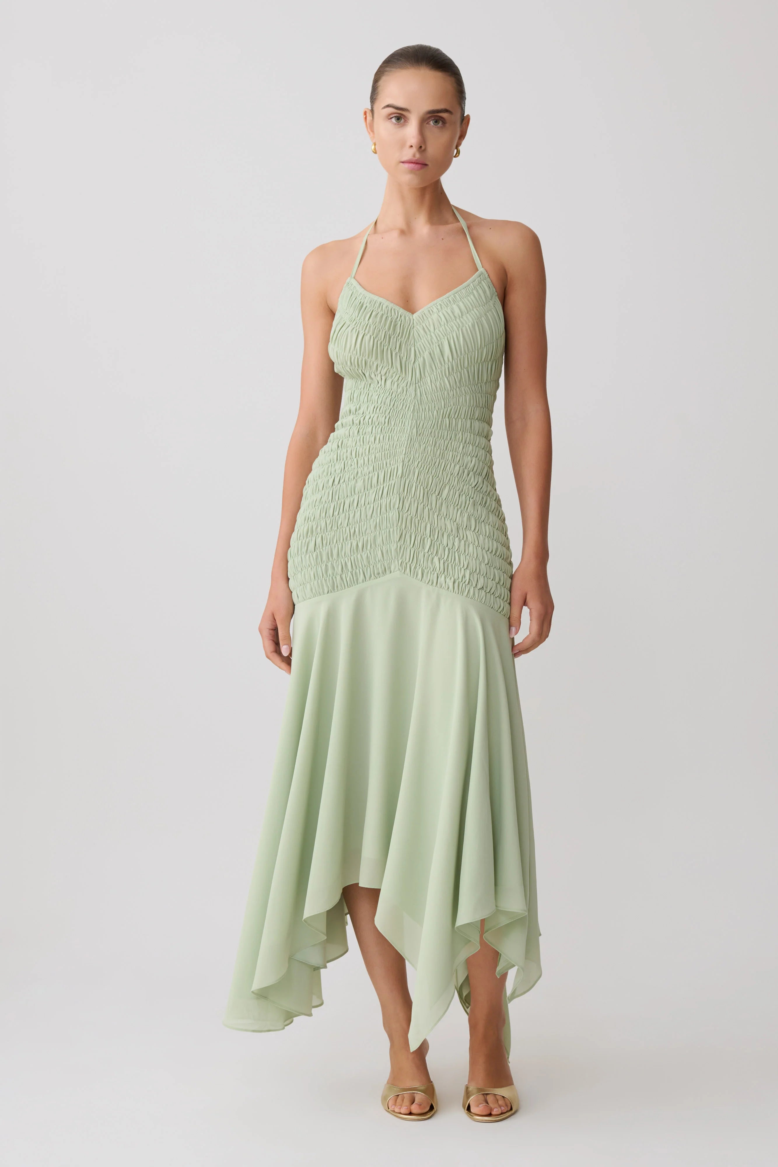 Woman wearing pale green halterneck maxi dress with shirred bodice and asymmetrical hem — Meshki | Endless UAE
