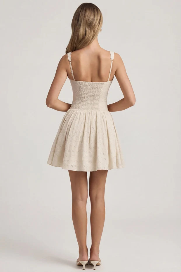Woman wearing cream broderie anglaise A-line mini dress with bow detail and strappy sandals — Oh Polly | Endless UAE