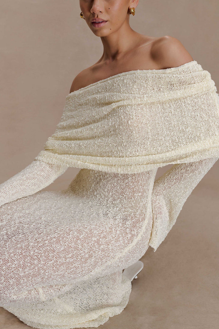 Woman wearing cream off-shoulder boucle maxi dress with draped sleeves and gold woven handbag — Meshki | Endless UAE