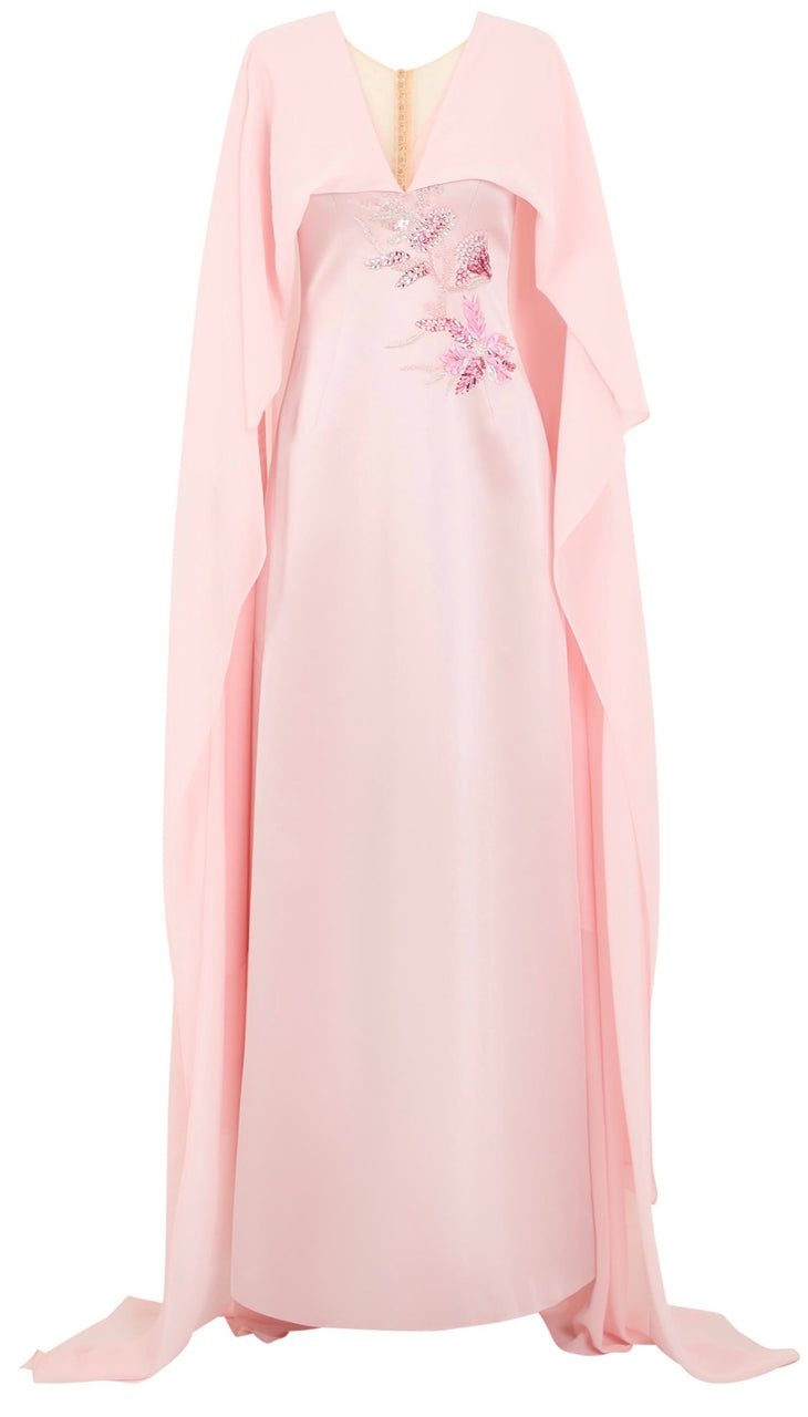 Woman wearing blush pink flowing gown with floral embellishment and draped cape at lakeside sunset — Tracy Studio | Endless UAE