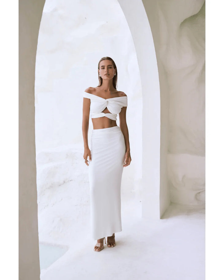 Woman wearing white off-shoulder crop top and maxi skirt in modern architectural setting — By Alle | Endless UAE