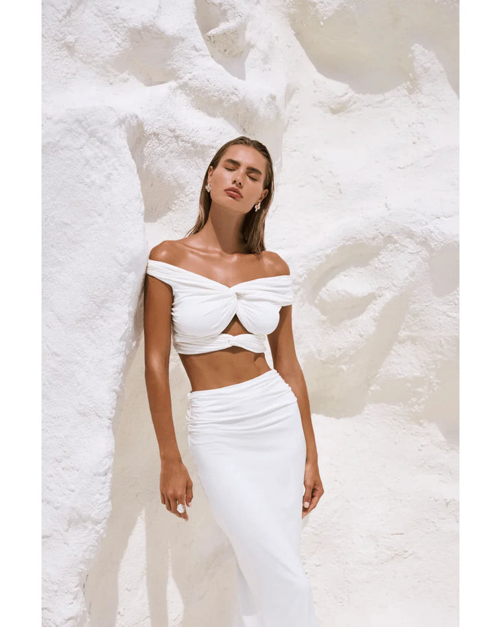 Woman wearing white off-shoulder crop top and maxi skirt in modern architectural setting — By Alle | Endless UAE