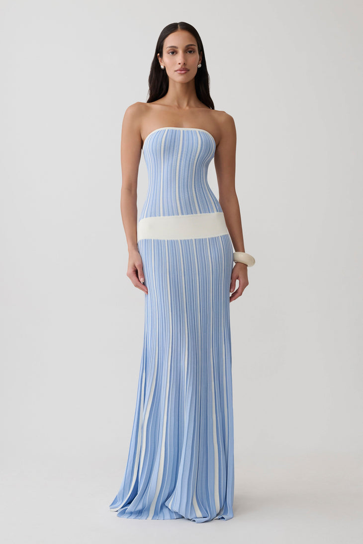 Woman wearing light blue striped strapless maxi knit dress with cream belt and white clutch — Meshki | Endless UAE