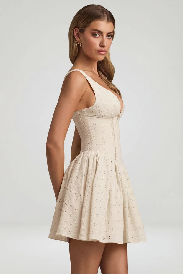 Woman wearing cream broderie anglaise A-line mini dress with bow detail and strappy sandals — Oh Polly | Endless UAE