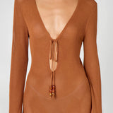 Woman wearing a caramel brown ribbed knit maxi dress with deep V-neckline and tie detail — HYPHEN | Endless UAE