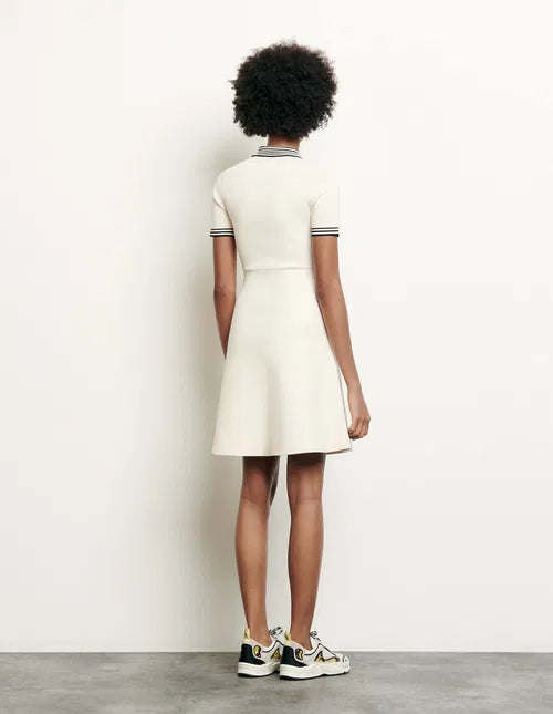 Woman wearing cream polo-style knitted dress with striped trim, sitting on chair — Sandro | Endless UAE