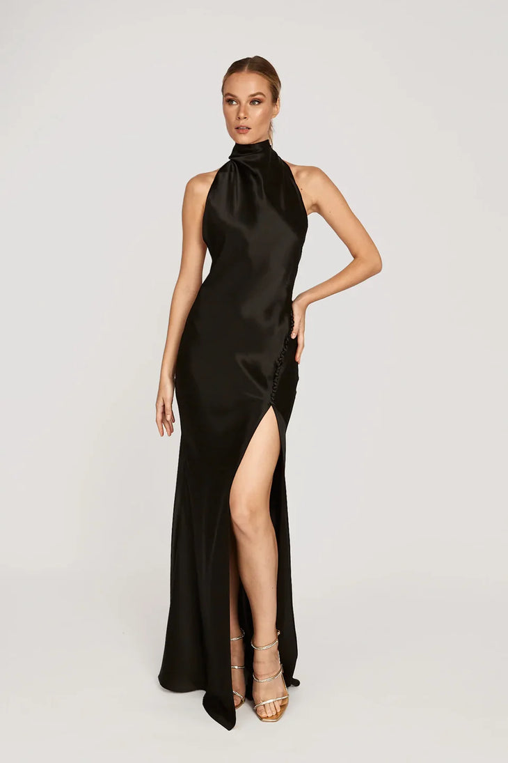 Woman wearing black halter satin gown with high slit and gold strappy heels — Sau Lee | Endless UAE