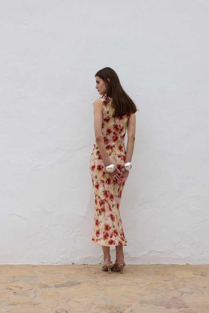 Woman wearing red floral midi dress against white wall — De La Vali | Endless UAE
