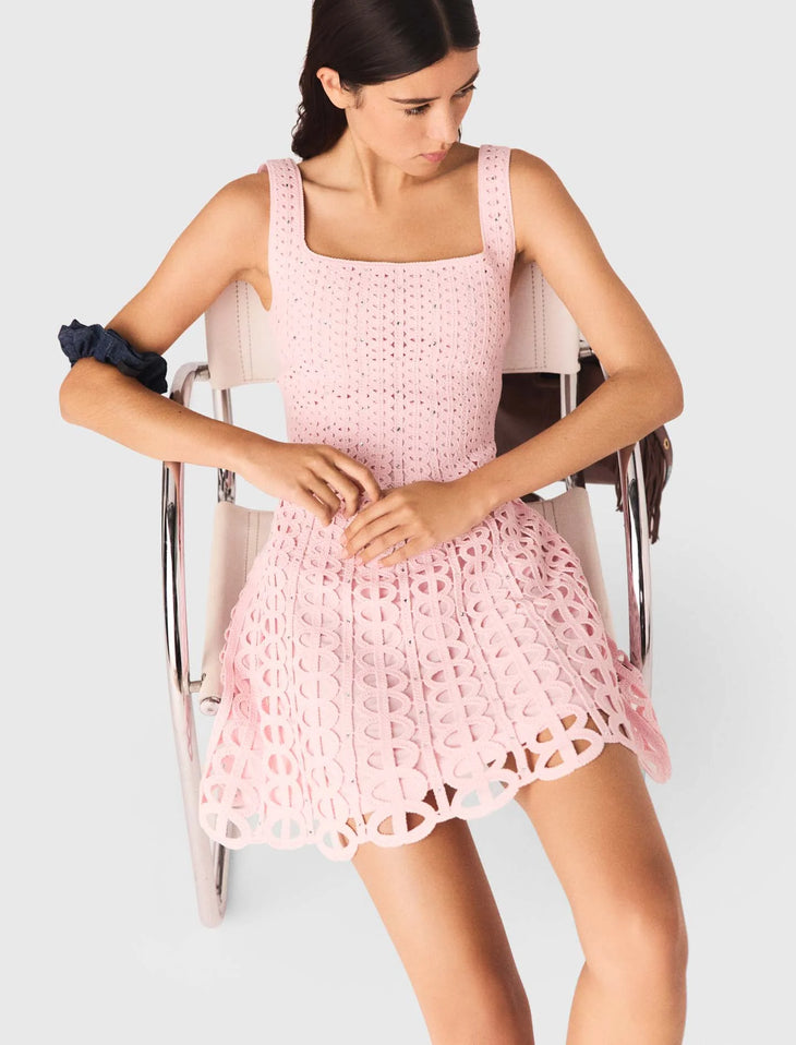 Woman wearing pink rhinestone crochet dress with navy ruffle sleeves and brown shoulder bag — Maje | Endless UAE