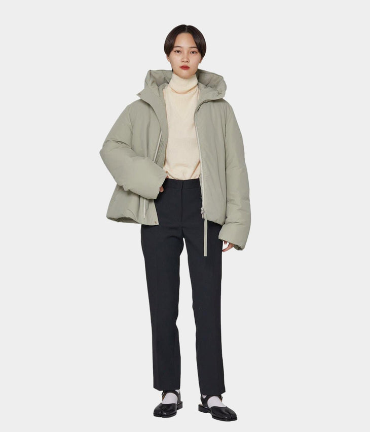 Beige puffer jacket with hood worn over dark trousers, back view — Jil Sander | Endless UAE