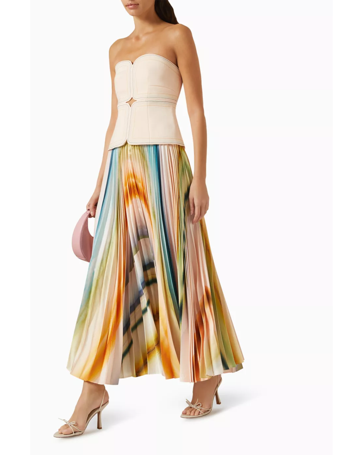 Woman wearing cream strapless top with colorful pleated midi skirt and neutral sandals — Acler | Endless UAE