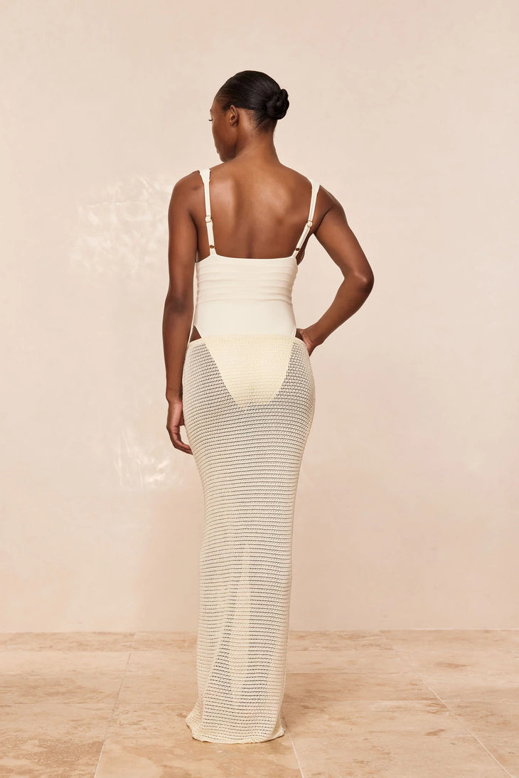 Woman wearing cream fitted midi skirt with matching bikini top and sheer shirt by the ocean — Monday Swimwear | Endless UAE
