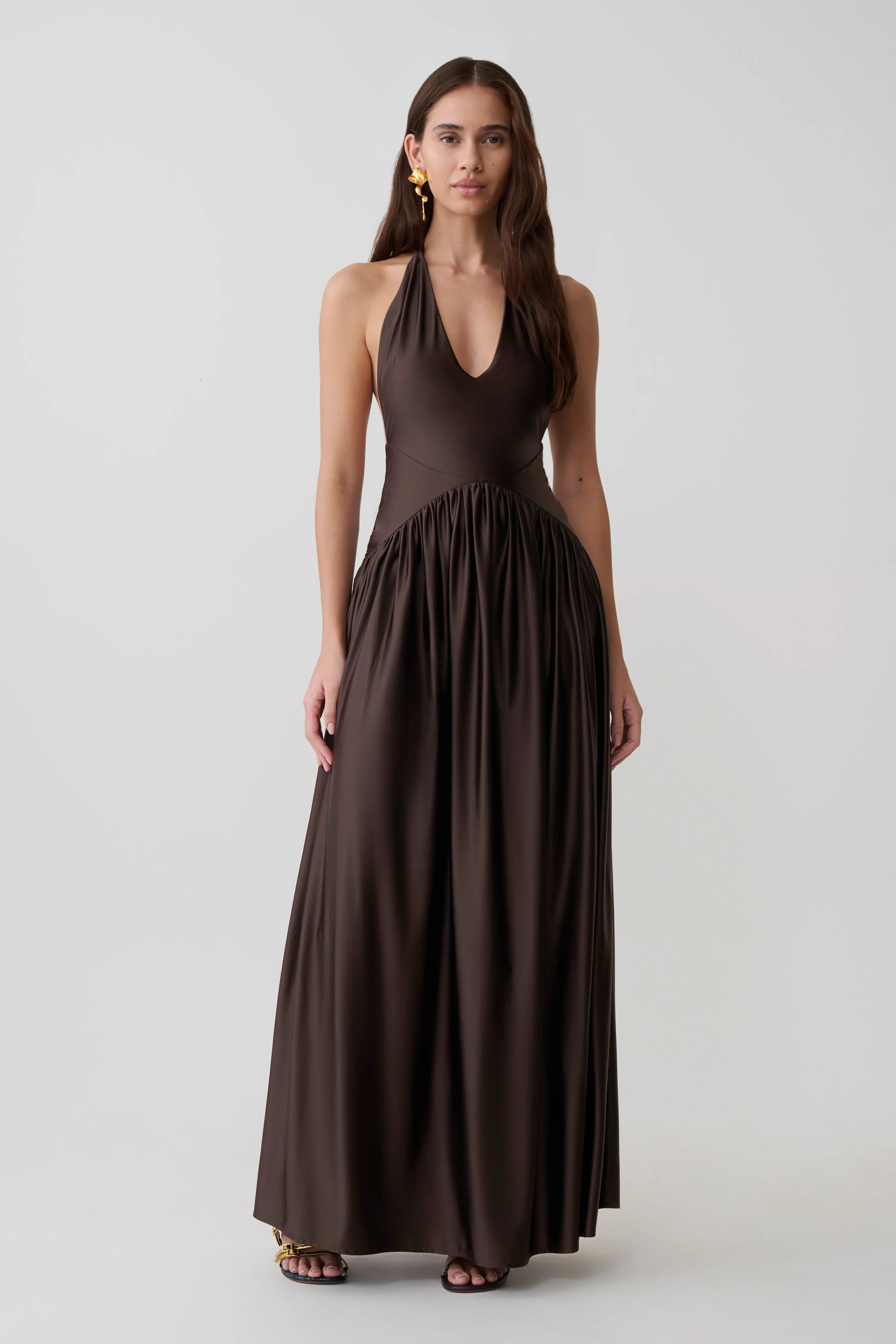 Woman wearing brown halter maxi dress with pleated skirt and gold heeled sandals — Meshki | Endless UAE